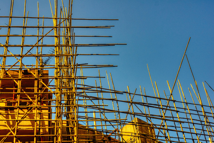 Beyond the Naked Eye: How Predictive Maintenance Is Redefining Structural Safety Yenem Structural Engineers Bamboo scaffolding on a building under construction against a clear blue sky showing expertise in predictive maintenance.