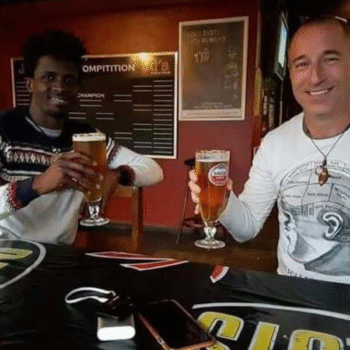 Two men toasting beers at a bar. Sponsor child success story.
