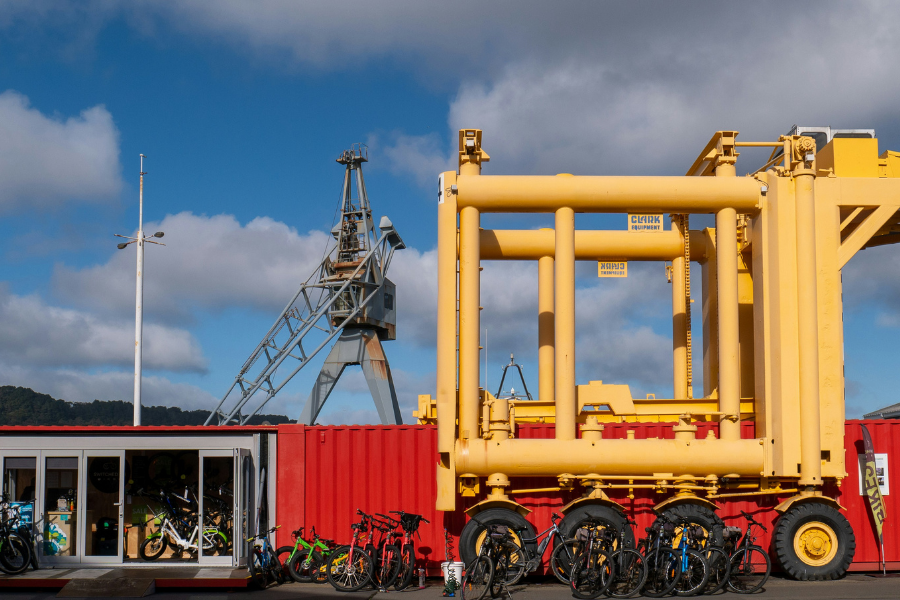Transport Frames: The Strategy Behind Seamless Global Logistics Yenem Structural Engineers Bright yellow transport frames next to a red container with bikes, plus an industrial crane in the background.
