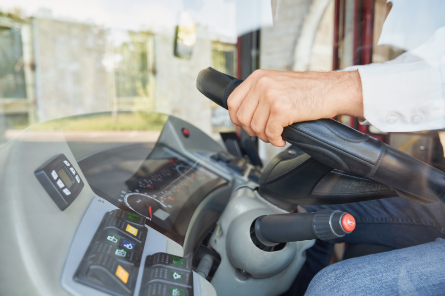 Heavy Duty, Zero Doubt: The Technical Security Behind Verified Transport Frames Yenem Structural Engineers Bus driver's hand on steering wheel, dashboard visible. Technical security in verified transport.