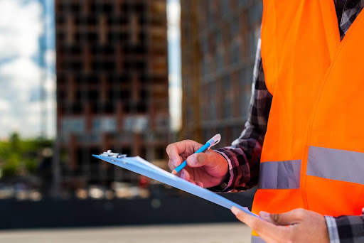 Less Guesswork, More Confidence: What Asset Owners Want from Asset Inspections Yenem Structural Engineers Construction worker in safety vest filling out a form on a clipboard for asset inspections.